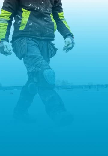 a roofer wearing protective clothing unrolling roofing material on a flat roof