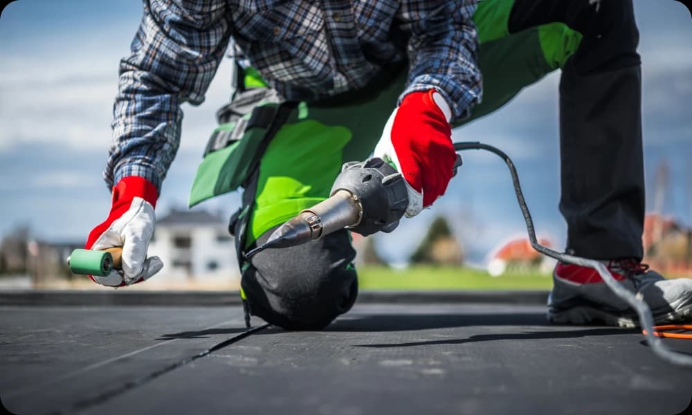 A roofer with tools working on a flat roof 