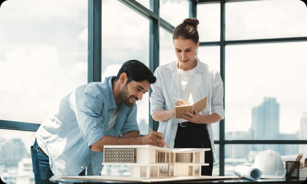 A male architect looking at a conceptual design with a female architect making notes