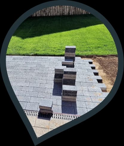 stone paver patio installation in progress with drainage installed