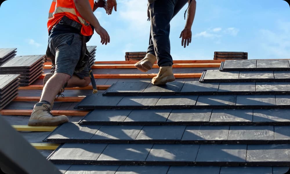two roofers installing slate tiles onto a brand new roof 