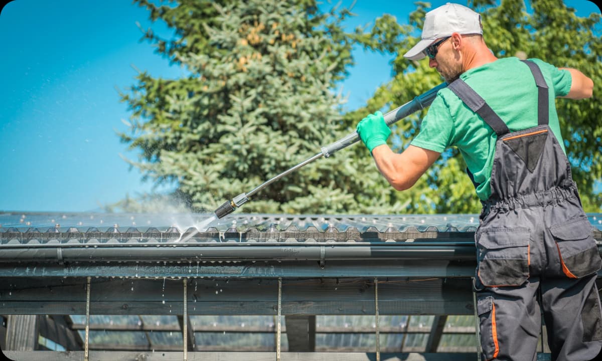 professional gutter cleaning using a high-pressure washer to dislodge clogs