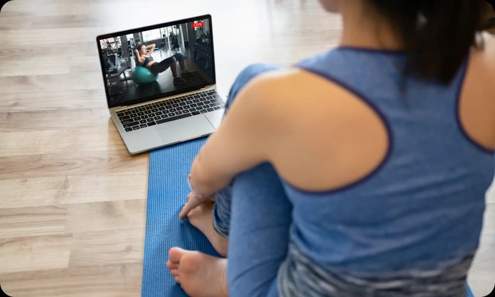  an online personal trainer guiding her client through the use of a pilates ball