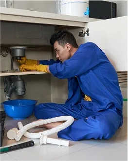 Plumber fixing pipes under sink