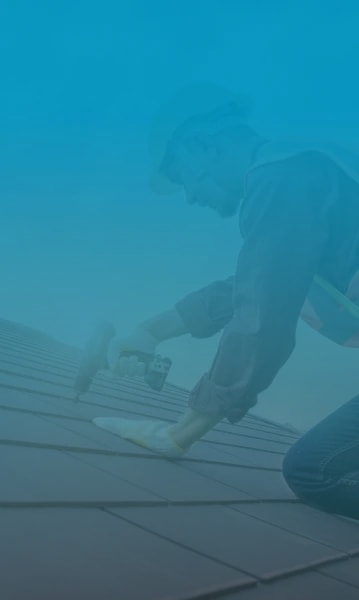 A roofer installing a new roof by securing clay tiles with a drill