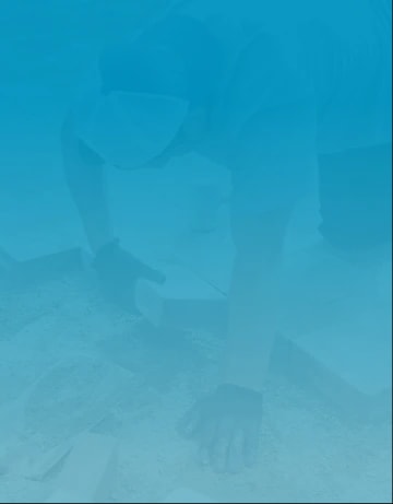 Expert patio installer with gloves on, laying paver bricks on large patio